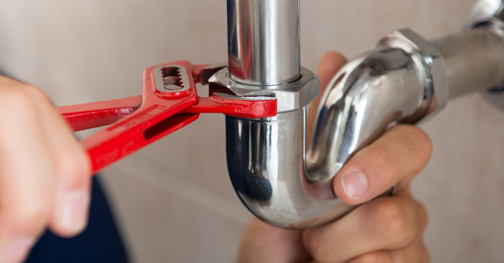 man fixing pipe with wrench